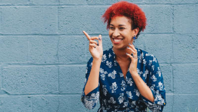Woman pointing and laughing with blue wall background